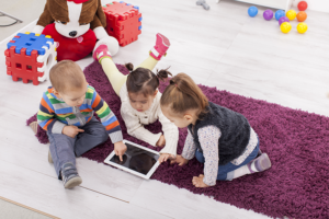kids playing at a daycare with a tablet during drop in care